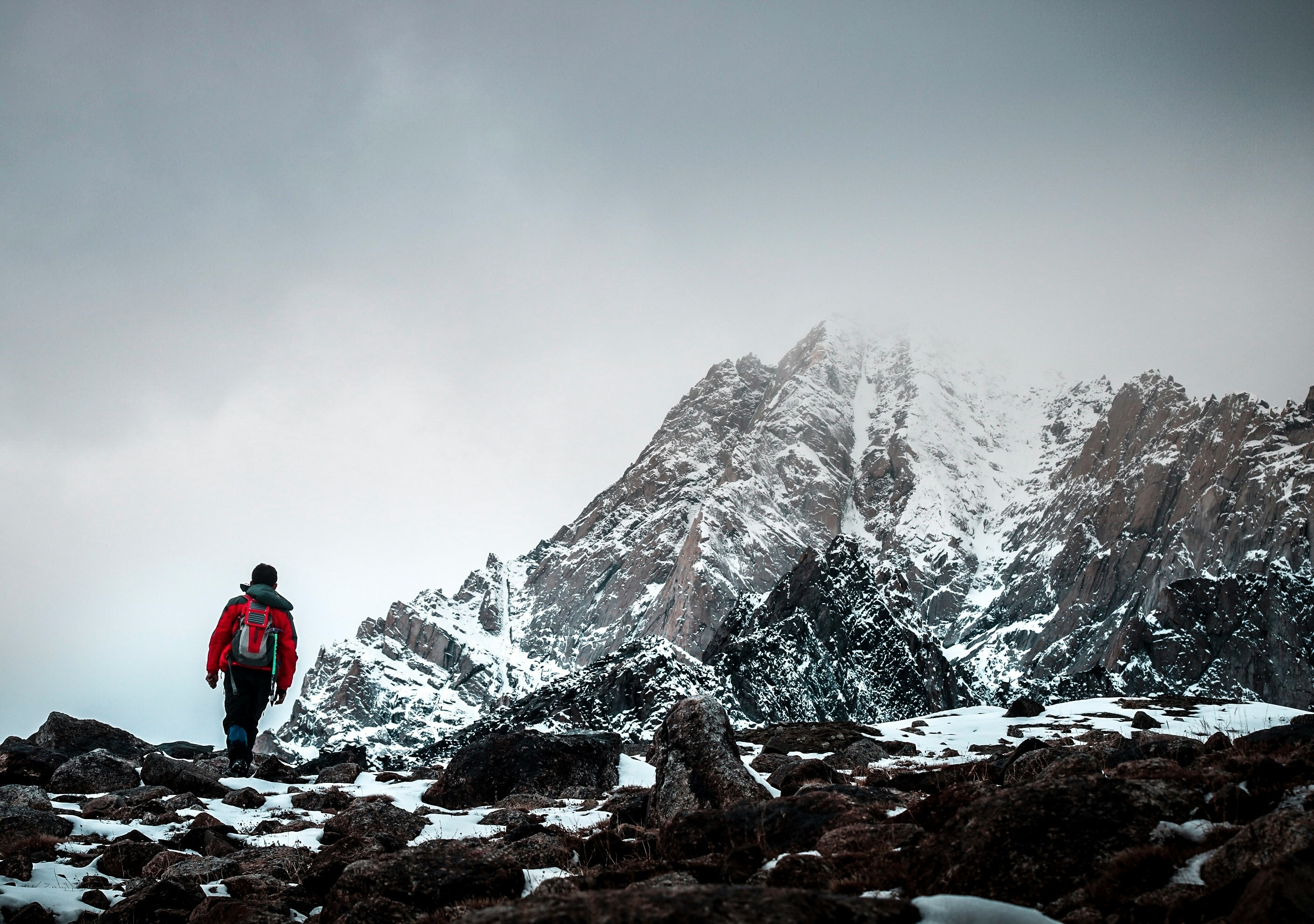 man in red jacket standing on rocky mountain during daytime